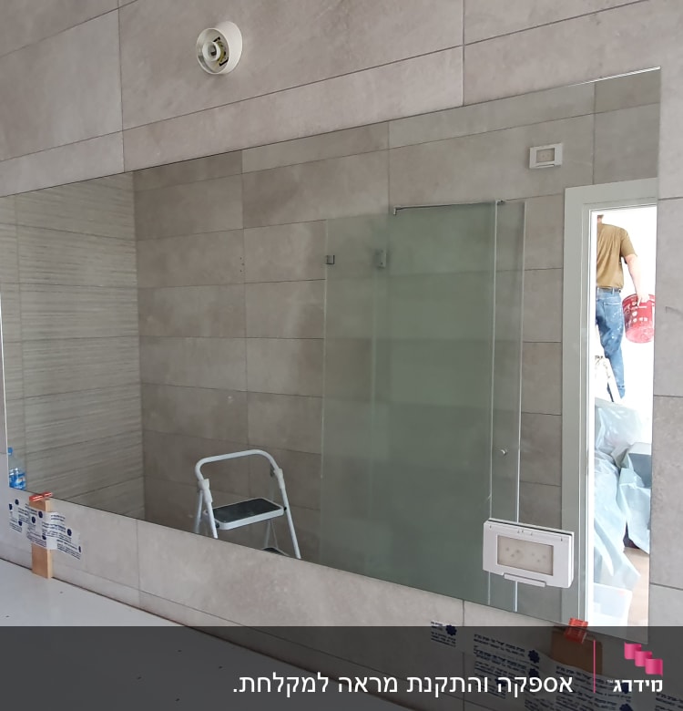 מראה גדולה על קיר עם זכוכית מקלחת